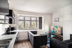 a kitchen with a living room with a couch and a tv at Spacious 2 Bed Apartment in Waterloo Liverpool in Waterloo