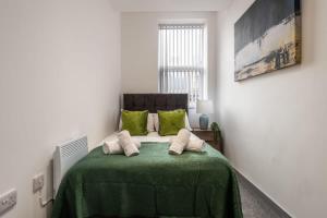 a bedroom with a bed with a green blanket at Smart 2 Bed Budget Apartment in Central Doncaster in Doncaster