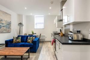 a living room with a blue couch and a kitchen at Smart 2 Bed Budget Apartment in Central Doncaster in Doncaster