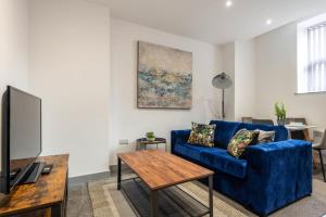 a living room with a blue couch and a table at Smart 2 Bed Budget Apartment in Central Doncaster in Doncaster