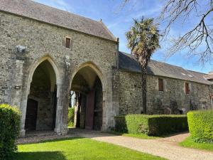 an exterior view of a stone building with a palm tree at ABBAYE DE BLANCHELANDE in Neufmesnil