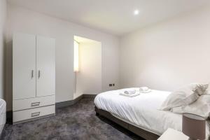 a white bedroom with a bed and a cabinet at Smart 1 Bed Budget Apartment in Darlington in Darlington