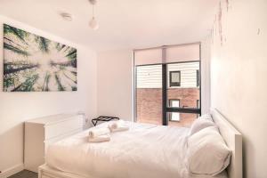 ein weißes Schlafzimmer mit einem Bett und einem großen Fenster in der Unterkunft Spacious & Modern 1 Bed Apartment Manchester in Manchester