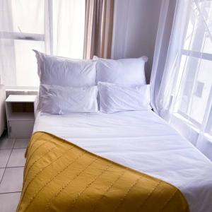 uma cama grande com almofadas brancas e uma janela em CityHome Luxurious Apartment em Pretoria