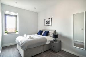 a bedroom with a bed with blue pillows and a window at Modern & Spacious 2 Bed Apartment in Waterloo Liverpool in Waterloo