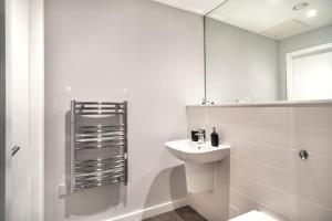 een witte badkamer met een wastafel en een spiegel bij Modern & Spacious 2 Bed Apartment in Waterloo Liverpool in Waterloo