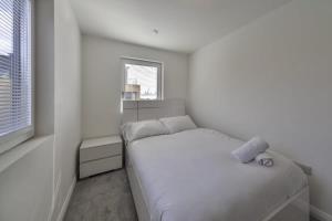 a white bedroom with a bed and a window at Stylish and Bright 2 Bed Apartment in Ashford in Ashford