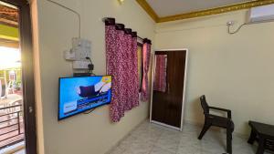Cette chambre dispose d'une télévision murale et de rideaux. dans l'établissement Coco Hut , Devbaug, à Malvan
