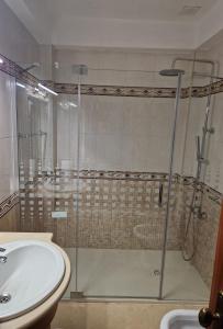 a bathroom with a glass shower and a sink at Sleep and Fly in Faro