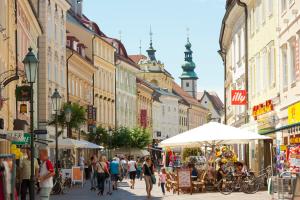 a group of people walking down a street with buildings at Cityhotel am Domplatz Self-CheckIn in Klagenfurt +50 photos