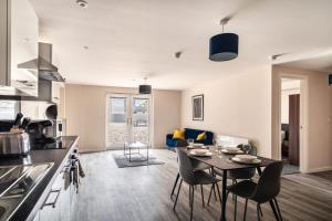 Il comprend une cuisine et un salon avec une table et des chaises. dans l'établissement Bright & Modern 2 Bed Apartment in Manchester, à Manchester