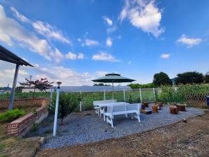 una panchina bianca e un ombrellone in giardino di 2022 New Entire house for family a Boseong