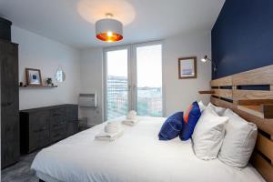 una camera da letto con un grande letto con cuscini bianchi e blu di Stunning 2 Bed Flat 5min to Old Trafford Stadium a Manchester