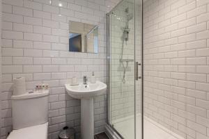 a white bathroom with a sink and a shower at Stunning 2 Bed Flat 5min to Old Trafford Stadium in Manchester