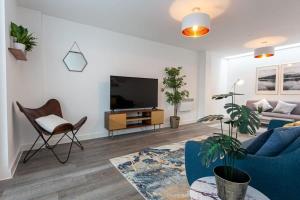 sala de estar con sofá azul y TV en Amazing 2 Bed Apartment 5min To Old Trafford, en Mánchester