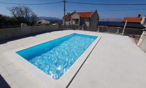 a swimming pool with blue water in a backyard at Apartmani Naomi&Leo in Senj