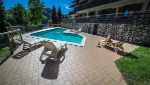 a person sitting in a chair next to a swimming pool at Residence Panorama in Molina di Ledro