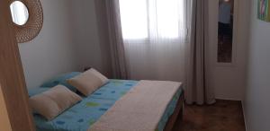 1 dormitorio con cama con almohadas y ventana en Locations Alpinia Réunion, en Saint-Paul
