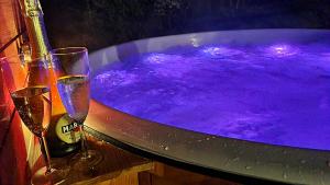 two champagne glasses and a tub with purple water at Domki Na Wzgorzu in Nowica