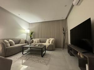 ein Wohnzimmer mit einem Sofa und einem Tisch in der Unterkunft سويت انيق بقفل ذكي بحي العقيق in Riad