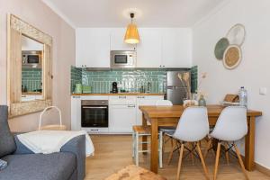 a kitchen with a wooden table and white cabinets at Casinha da Jade in Albufeira