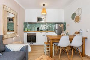 una cucina con un tavolo in legno e mobili bianchi di Casinha da Jade ad Albufeira