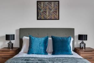 1 dormitorio con 1 cama con almohadas azules y 2 lámparas en Bright 1 Bedroom Apartment, Central Birmingham, en Birmingham