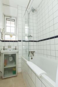 uma casa de banho em azulejos brancos com uma banheira e um lavatório. em Lovely 2 Bedroom Apartment in Waterloo em Londres