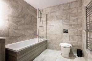 a bathroom with a tub and a toilet and a sink at Modern 3 Bed Budget Apartment in Central Doncaster in Doncaster