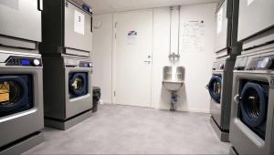 una lavandería con 2 lavadoras y un urinario en Forenom Hostel Lund Örtofta, en Eslöv