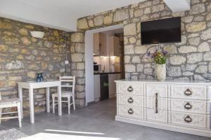Habitación con tocador blanco y TV en una pared de piedra. en Coastal Stone Hideaway with Stunning Scenery, en Kitriaí