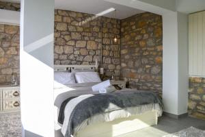 sypialnia z kamienną ścianą i łóżkiem w obiekcie Coastal Stone Hideaway with Stunning Scenery w mieście Kitriaí