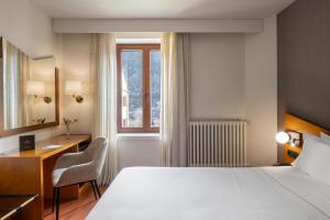 a bedroom with a bed and a desk and a window at Hotel de l'Isard in Andorra la Vella
