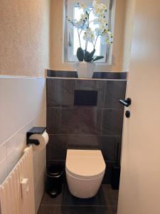 La salle de bains est pourvue de toilettes et d'une fenêtre ornée d'un vase de fleurs. dans l'établissement Apartment M - Zell am See, à Zell am See