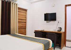 a bedroom with a desk and a bed and a tv at Blue Castle Inn in Greater Noida