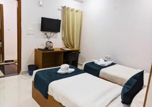 a room with two beds and a desk with a television at Blue Castle Inn in Greater Noida