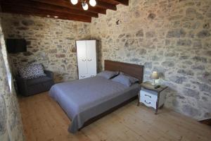 a bedroom with a bed and a chair in a stone wall at Malia Stone Residence - Secluded Cozy Retreat in Goníai