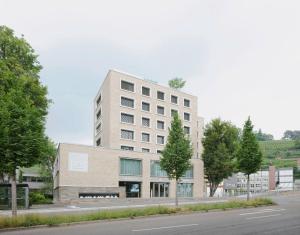 ein hohes weißes Gebäude mit Bäumen davor in der Unterkunft MAVO Hospitality by Büroma Apart Apartmentvermietung GmbH Esslingen in Esslingen