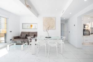 une salle à manger blanche avec une table et des chaises en verre dans l'établissement Penthouse Ancla 561 Levante Beach, à Benidorm