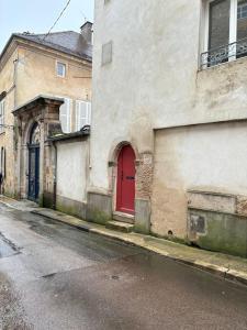 ein altes Gebäude mit einer roten Tür auf einer Straße in der Unterkunft La Tournelle in Langres