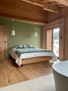 L'Alcôve - Chalet avec Piscine في كسونبورت-لونجمير: غرفة نوم بسرير كبير في غرفة خشبية
