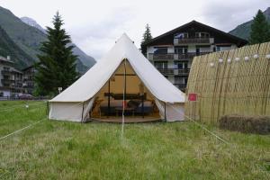 biały namiot na polu z budynkiem w obiekcie Camp Pera w mieście Täsch