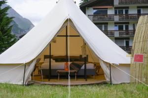 a bell tent with a bed and a balcony at Camp Pera in Täsch