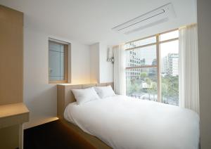 a bedroom with a large white bed and a window at UH Suite Seoul Deoksugung in Seoul