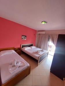 2 camas en una habitación con una pared roja en Velmar Hotel, en Golem