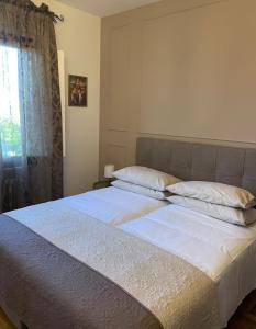 uma cama com lençóis brancos e almofadas num quarto em Residenza Sandrini em Gambassi Terme