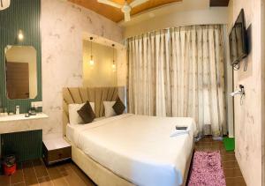 a bedroom with a large white bed and a sink at Hotel Grand Nidhivan in Nagpur