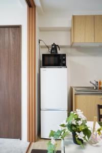 a microwave sitting on top of a refrigerator in a kitchen at The Peak Chiyozaki in Osaka