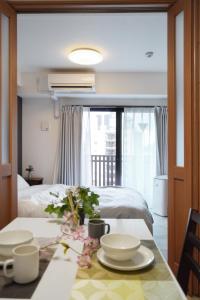 ein Zimmer mit einem Bett und einem Tisch mit Geschirr darauf in der Unterkunft The Peak Chiyozaki in Osaka