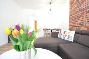 una sala de estar con sofá y un jarrón de flores en Apartment Fragrantly, en Poprad
